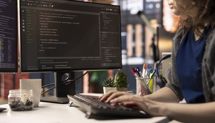 Professional software developer types code on a laptop in a sleek workspace. Expert IT freelancer doing remote work on app development, software engineering and agile coding practices.