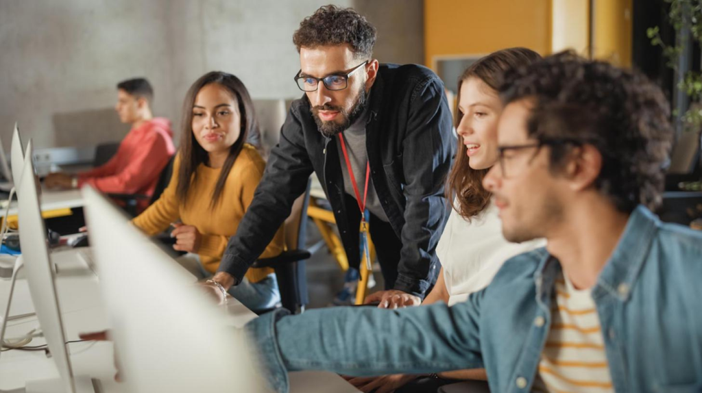 Alumnos participando en una formación in company frente a ordenadores, desarrollando habilidades de IA, datos y liderazgo